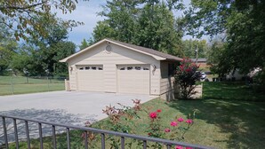 A garage with two doors, a small attached shed, and a well-maintained lawn with pink flowers. - Discover Maryville and the Great Smoky Mountains (Maryville)