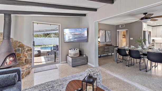 A modern kitchen with a dining area, a stone fireplace, and a TV mounted on the wall. - Bahama Breeze | Private Pool w/ Patio + Outdoor TV! (Sarasota)