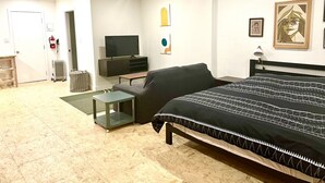 Ein modernes Schlafzimmer mit Bett, Fernseher, einem kleinen Tisch und einer Heizung.