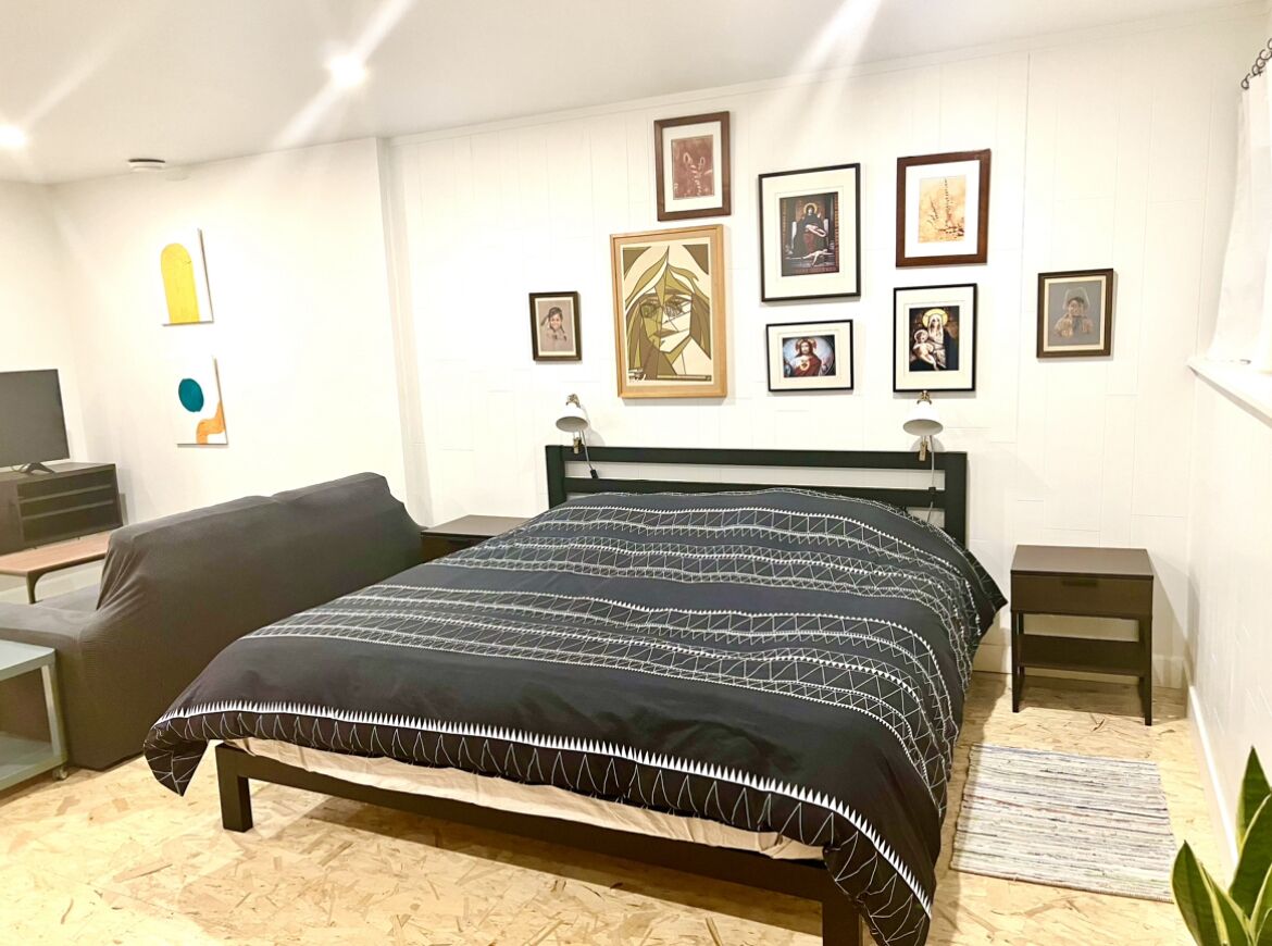 Een slaapkamer met een bed, een bank, een televisie en kunst aan de muur.