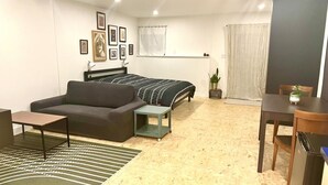 Ein gemütlicher Wohnraum mit Bett, Sofa, Esstisch und einer kleinen Küchenzeile.