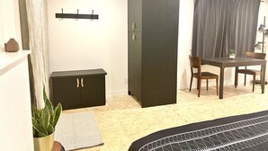 Ein Zimmer mit einem Bett, einem Schreibtisch, einem Stuhl, einem Kleiderschrank und einer Pflanze.