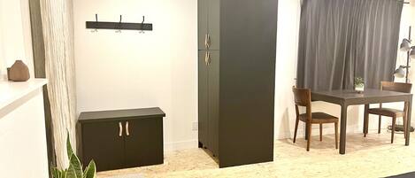 A room with a bed, a desk, a chair, a wardrobe, and a plant.