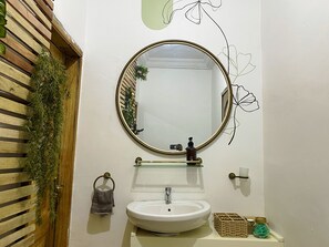 A bathroom with a round mirror, a sink, and a towel rack.