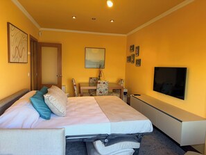 Une chambre d’hôtel avec un lit, un bureau, une chaise, une télévision et une porte.