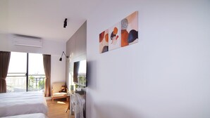 Quarto de hotel com duas camas, televisão, ventoinha e varanda com cortinas.