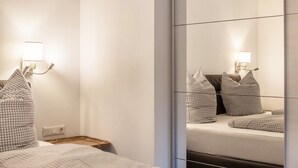 A hotel room with a bed, checkered pillows, a nightstand, and wall-mounted lamps.