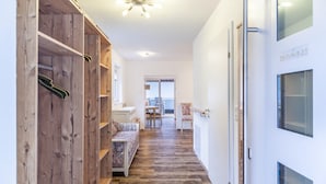 A hallway with wooden shelving units, a sofa, and a door with a window.