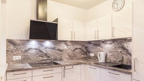 A kitchen with marble countertops, stainless steel appliances, and white cabinetry.
