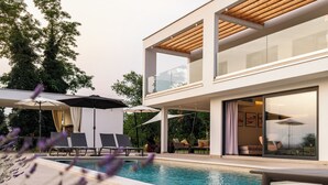 Un área moderna junto a la piscina con sillones reclinables, piscina y un edificio de dos pisos con amplias ventanas y techo de madera.