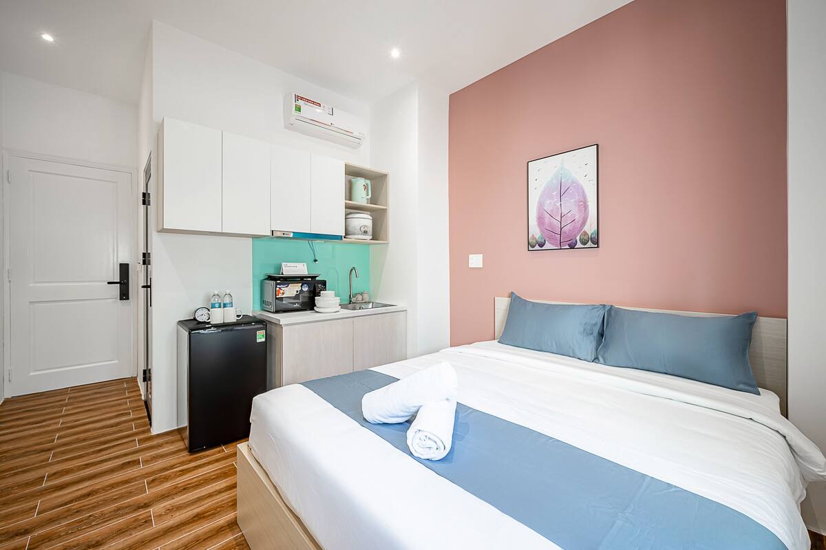 A hotel room with a bed, a small kitchenette, and a bathroom.