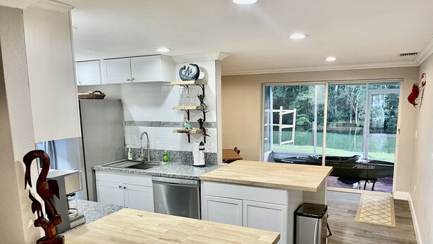 A modern kitchen with white cabinets, a granite countertop, and a built-in dishwasher. There is a window providing a view of the outdoors. - Spring 12% Discount-April May: The Hidden Jim River Cottage -4 Kayaks (Spring Hill)