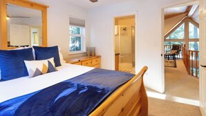 A bedroom with a bed, a ceiling fan, a window, and a door leading to a balcony.