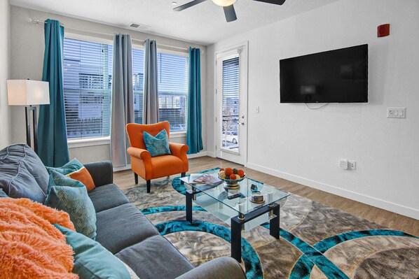 Una sala de estar moderna con sofá, sillón y mesa de centro de vidrio.