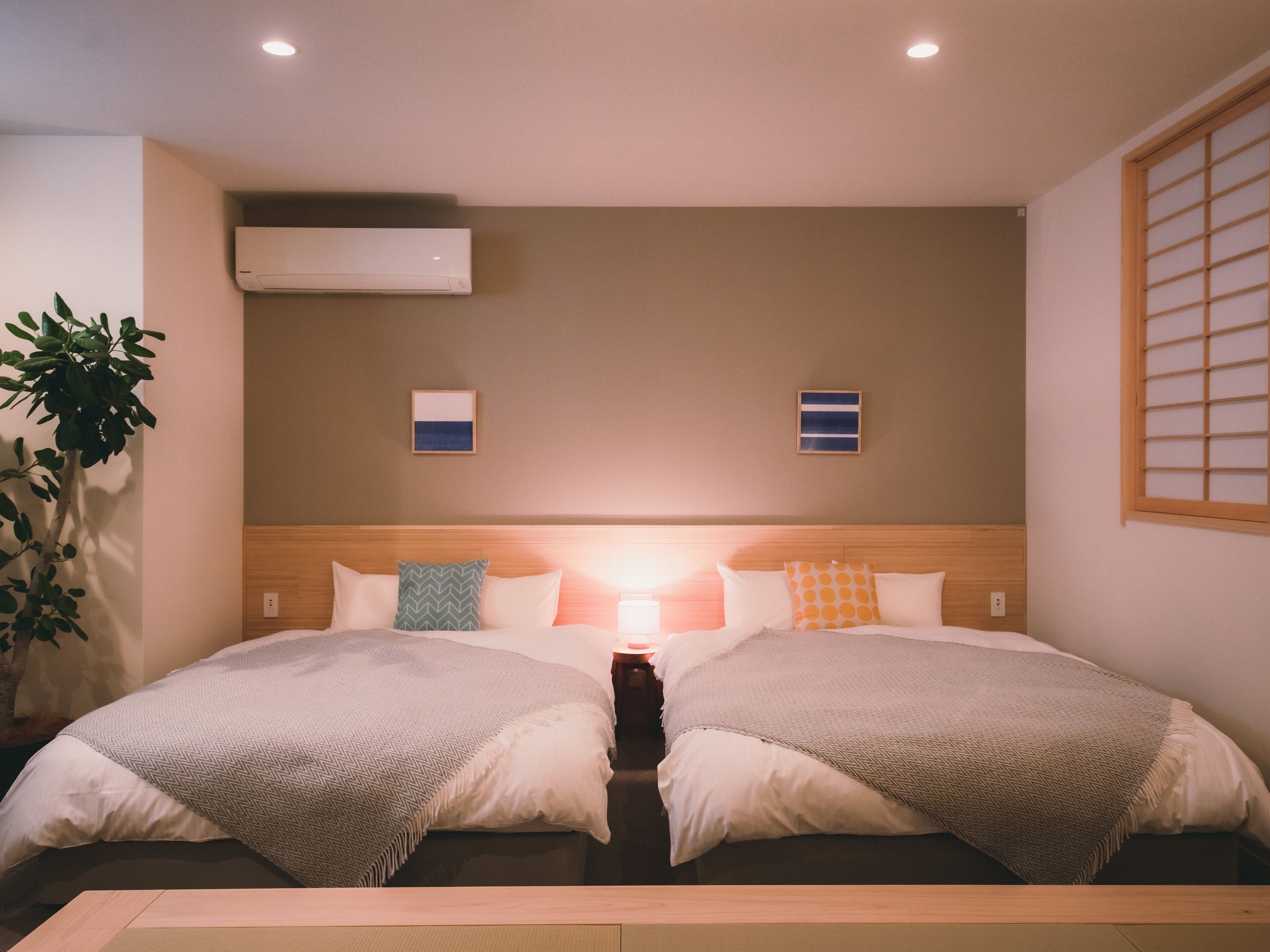 Ein Hotelzimmer mit einem großen Bett, zwei Wandklimaanlagen und einem Fenster mit einem Holzjalousie.