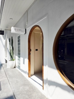 A building entrance with a sign reading 'GURL. STUDIO' and a potted plant. - Ascella Bangkok Hotel (Bangkok)