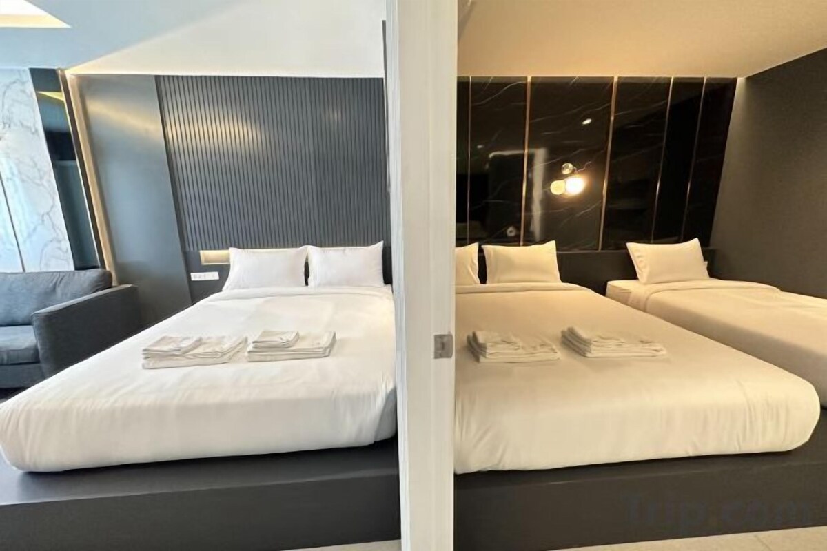 A modern hotel room with a large bed, a smaller bed, and a sofa.