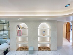 A modern interior with two arched shelving units, a small table, and a mirror. - Ascella Bangkok Hotel (Bangkok)