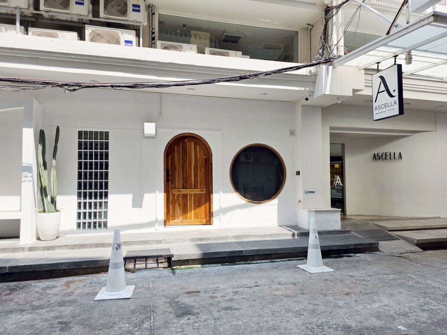 A building with a wooden door, a potted cactus, and a sign for Ascella Hotel.