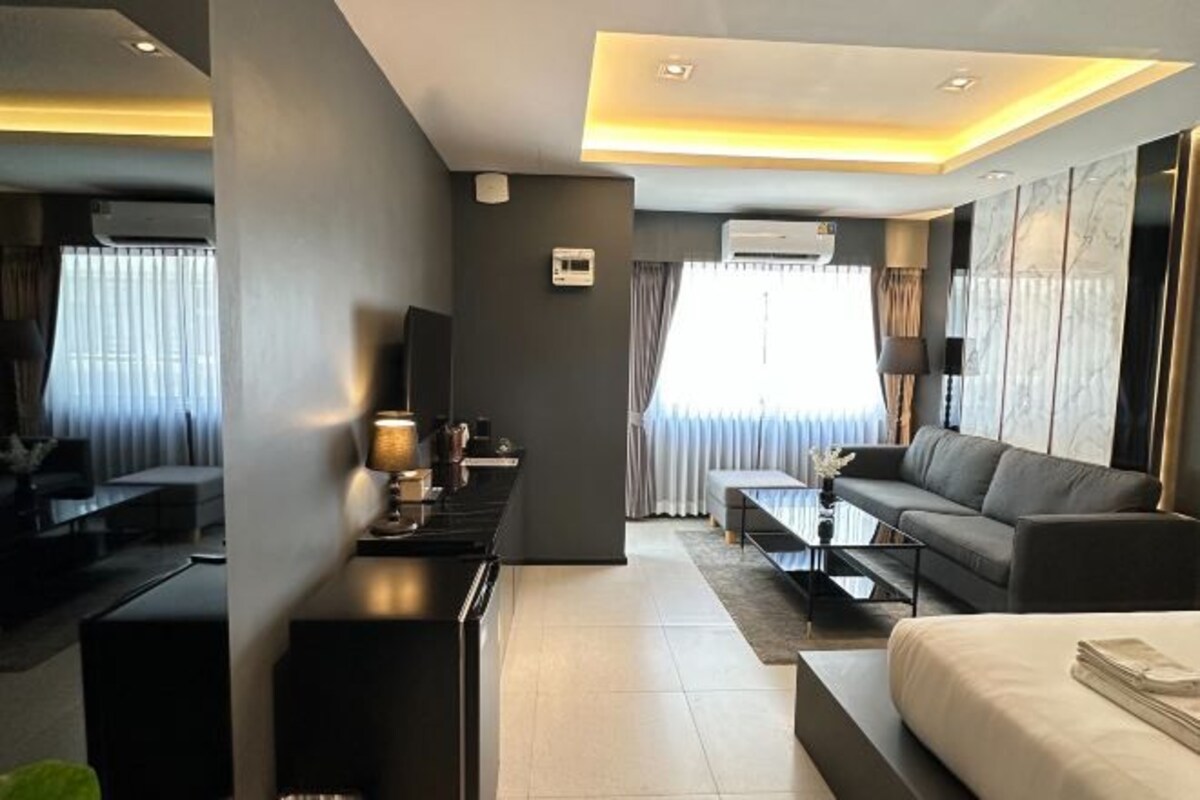 Una habitación de hotel moderna con un sofá, una cama, una mesita de café y un televisor.