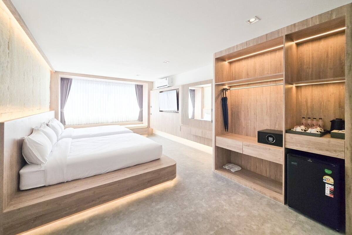 A modern hotel room with a large bed, built-in wardrobe, and a minibar.