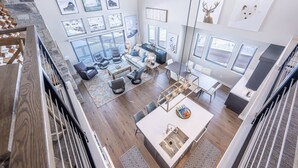 A spacious living area with a high ceiling, large windows, and a stone wall. - 2 Min to Deer Valley East Village | Luxury 5BR | Hot Tub | Sleeps 14 (Heber City)
