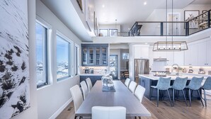 A spacious dining area with a long table, white chairs, and a view of the city. - 2 Min to Deer Valley East Village | Luxury 5BR | Hot Tub | Sleeps 14 (Heber City)