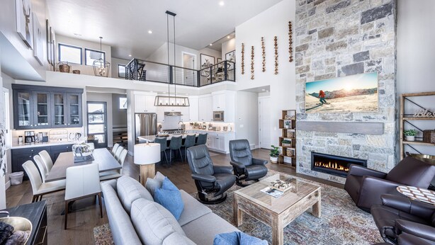 A spacious living area with a fireplace, seating, and a kitchen in the background. - 2 Min to Deer Valley East Village | Luxury 5BR | Hot Tub | Sleeps 14 (Heber City)