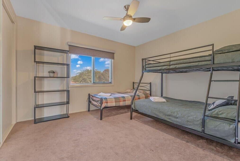 Une chambre avec des lits superposés, un ventilateur de plafond, une fenêtre avec vue et une bibliothèque.