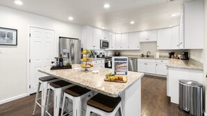 Une cuisine moderne avec des meubles blancs, un plan de travail en granit et des appareils électroménagers en acier inoxydable.