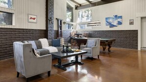 Un espace intérieur spacieux comprenant une table de billard, deux fauteuils et une table à manger.