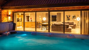 Una piscina con hidromasaje, un comedor y una sala de estar con sofás y una mesa de centro.