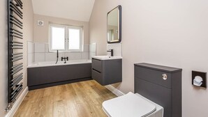 Ein modernes Badezimmer mit Badewanne, Waschtisch und Toilette.