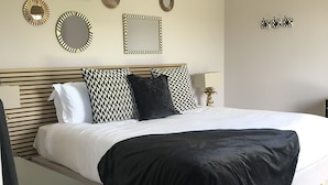 Une chambre à coucher avec un lit, des tables de chevet, une lampe et des éléments de décoration murale.