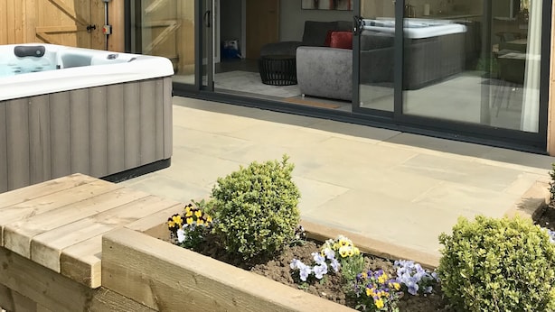 Une maison moderne avec une façade en bois, un jacuzzi et une terrasse agrémentée de fleurs.