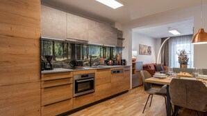 Een moderne keuken met houten kastjes, een inbouwoven en een groot raam met uitzicht op een bos.