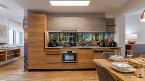Een moderne keuken met houten kastjes, een inbouwoven en een groot raam.