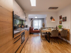 Enjoy a spacious living space with a kitchen, dining area, and seating area, featuring a large window and a wooden table.