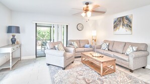 A living room with a sofa set, a coffee table, a lamp, a clock, and a painting on the wall. - South Tampa Retreat: Fenced Yard, Top Location! (Tampa)