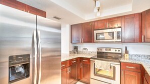A modern kitchen with stainless steel appliances, wooden cabinets, granite countertops, and a built-in oven. - South Tampa Retreat: Fenced Yard, Top Location! (Tampa)