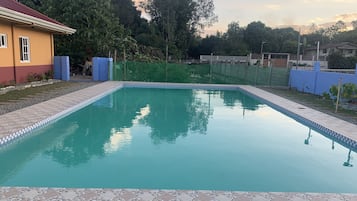 A rectangular swimming pool with a tiled edge, surrounded by a paved area with a pebble pattern.
