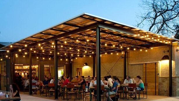 An outdoor patio area with tables and chairs, covered by a roof with string lights. - Scarlett Resorts at Laganas  (Bugallon)