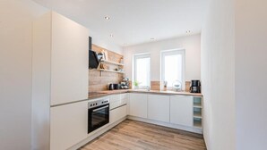 Una cucina moderna con mobili bianchi, un piano di lavoro in legno e un forno integrato.