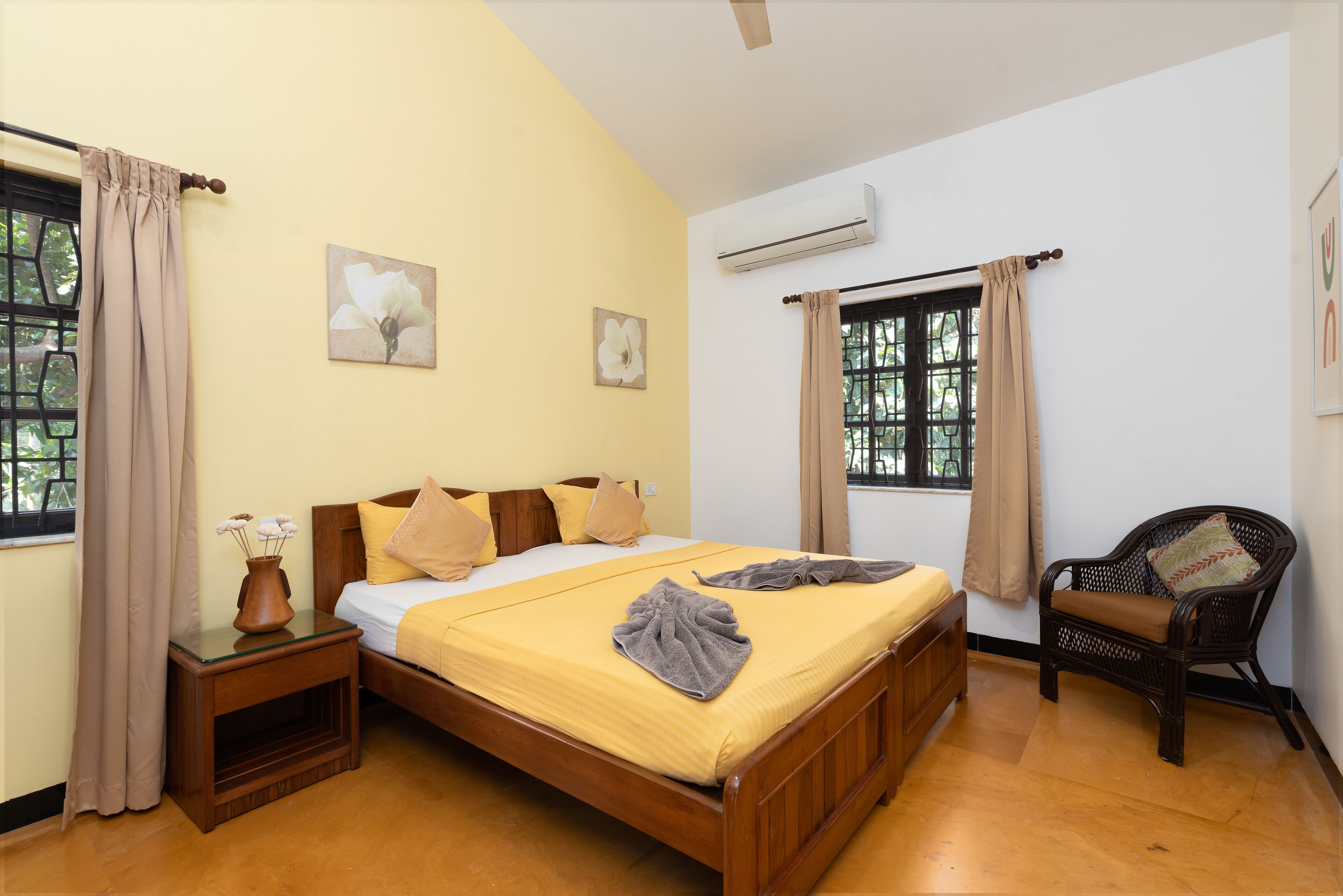 A room with a bed, a chair, a nightstand, and an air conditioner.