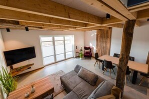 Un vaste espace de vie comprenant un grand canapé, une table à manger et un téléviseur fixé au mur.