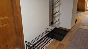 A hallway with wooden doors, a wall-mounted coat rack, and a striped rug on the floor.