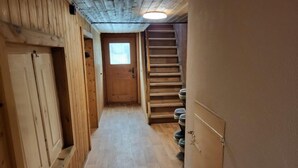 A narrow hallway with wooden walls and a wooden staircase.
