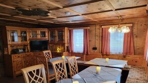 A wooden cabin with a dining area, kitchen, and a television.