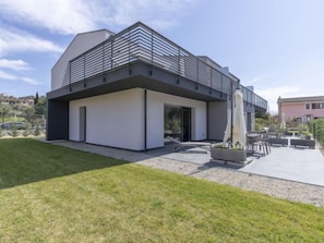 Un bâtiment moderne à deux étages, doté d’un toit plat et d’un balcon avec des lattes horizontales.