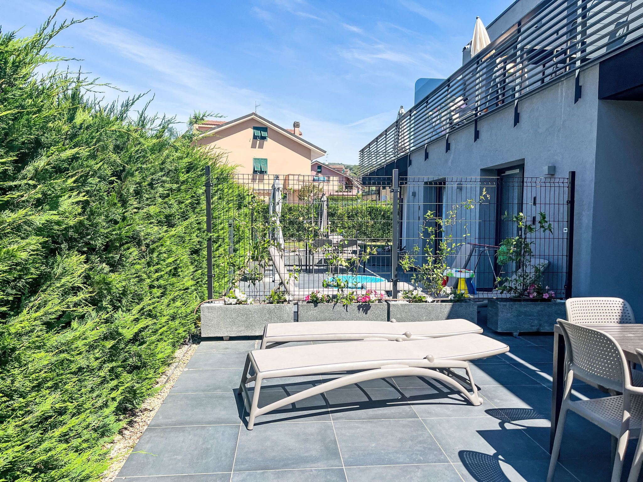 En terrasse med udendørs møbler, en pool og udsigt over et boligområde.
